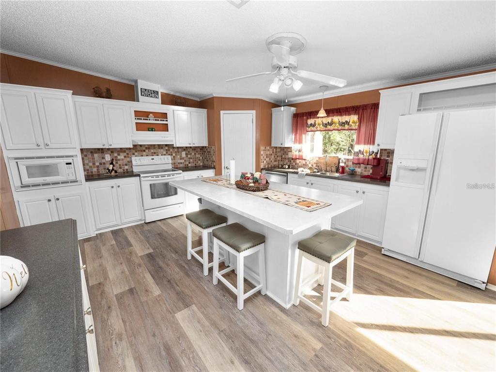 3201 Tenoroc Mine Road Lakeland, FL 33805 - Photo 18 of 48 a kitchen with stainless steel appliances granite countertop a stove top oven a sink dishwasher and white cabinets with wooden floor