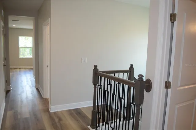 a view of a hallway with wooden floor and stairs