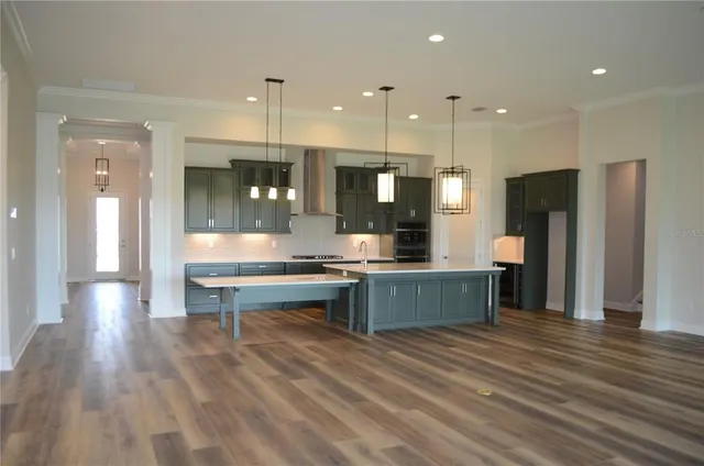 a kitchen with stainless steel appliances granite countertop a refrigerator a sink dishwasher a stove and a refrigerator with wooden floor