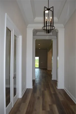 a view of a hallway with wooden floor and chandelier