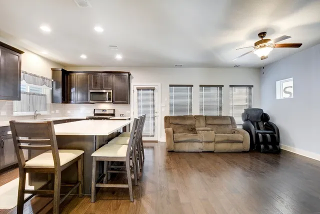 a living room with stainless steel appliances kitchen island granite countertop furniture and a wooden floor