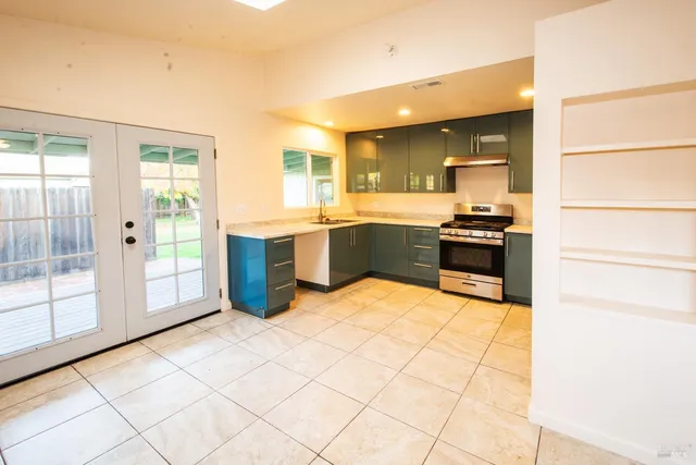 a large kitchen with stainless steel appliances a stove a sink dishwasher and a refrigerator with wooden floor