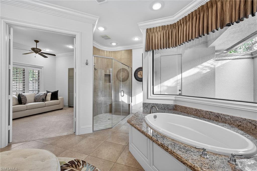 16488 Felicita Court Naples, FL 34110 - Photo 23 of 50 a bathroom with a tub a double vanity sink and glass door