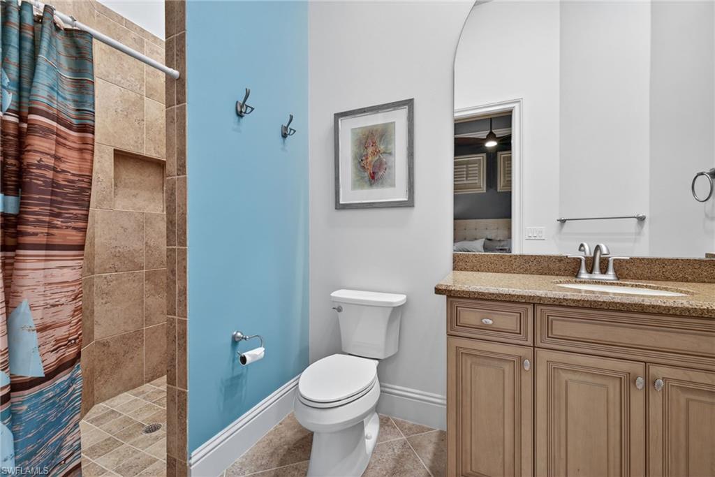 16488 Felicita Court Naples, FL 34110 - Photo 28 of 50 a bathroom with a granite countertop toilet a sink and a mirror