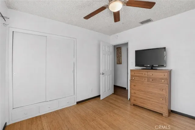 an empty room with wooden floor chandelier fan and windows
