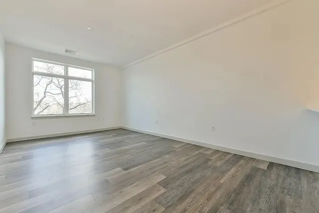 an empty room with wooden floor and windows
