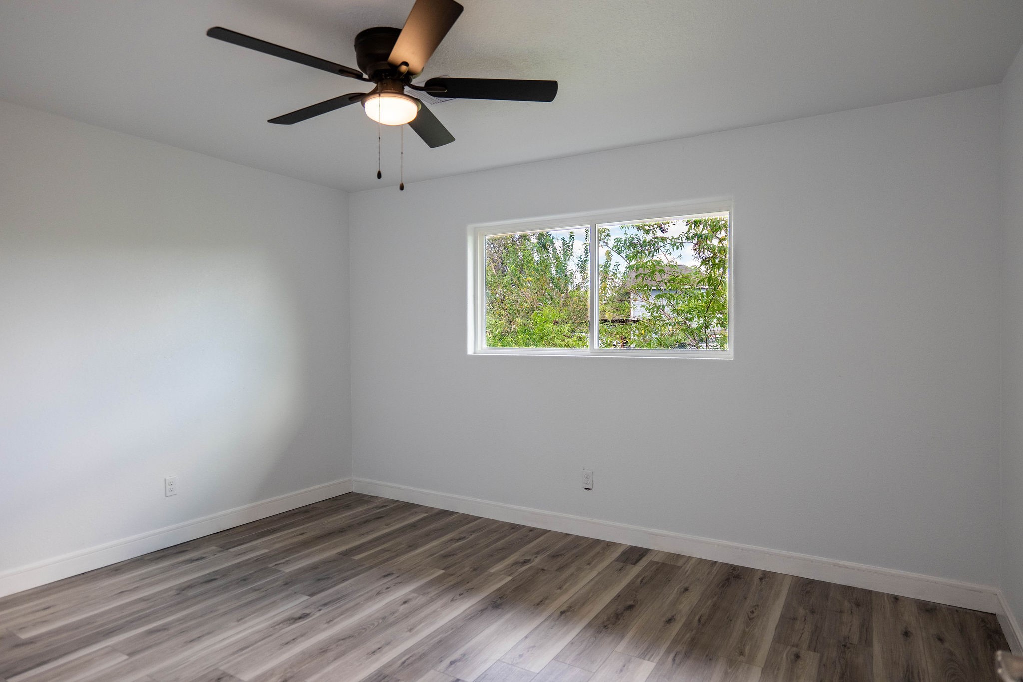 8718 Magna Street Houston, TX 77093 - Photo 11 of 33 an empty room with wooden floor ceiling fan and windows