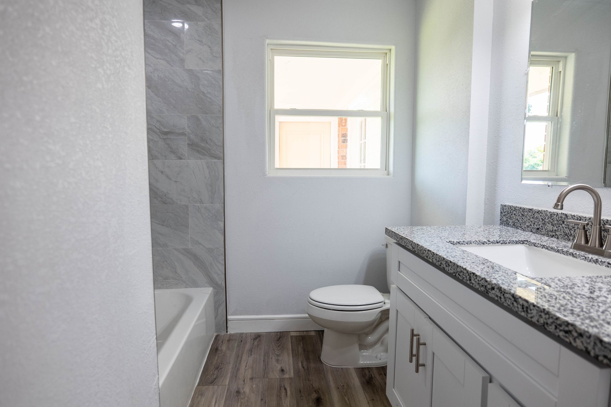 8718 Magna Street Houston, TX 77093 - Photo 16 of 33 a bathroom with a granite countertop toilet a sink and a bathtub