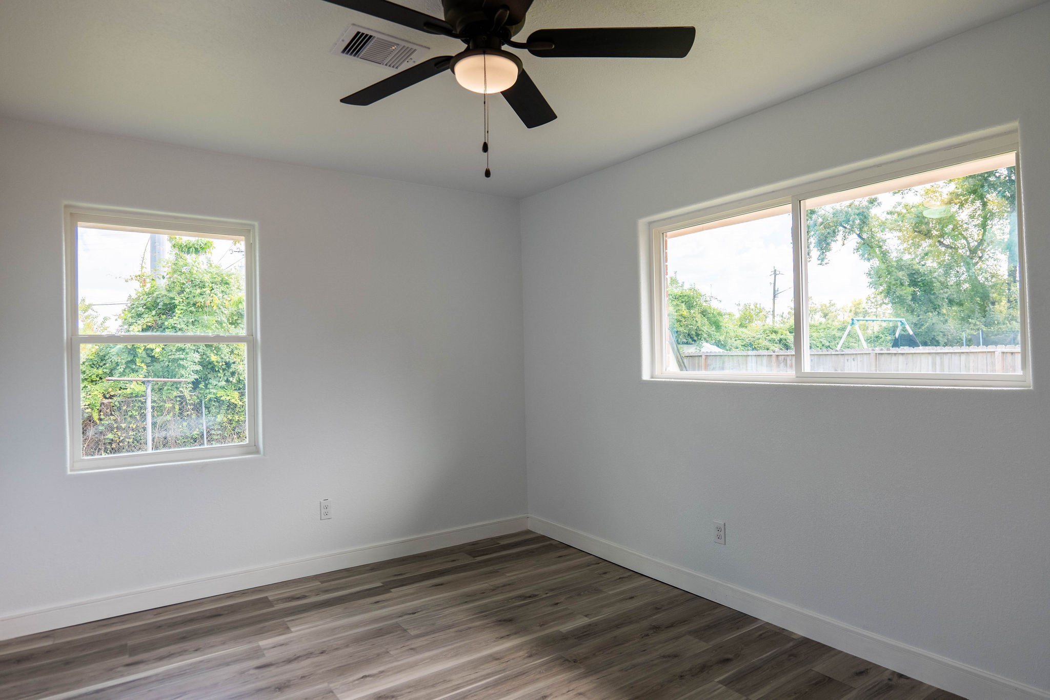 8718 Magna Street Houston, TX 77093 - Photo 21 of 33 an empty room with wooden floor ceiling fan and windows
