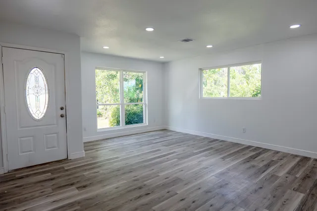 an empty room with wooden floor and windows