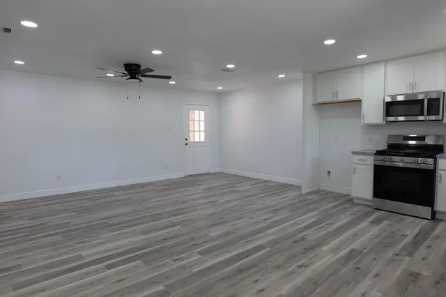 a view of an empty room with a window and wooden floor