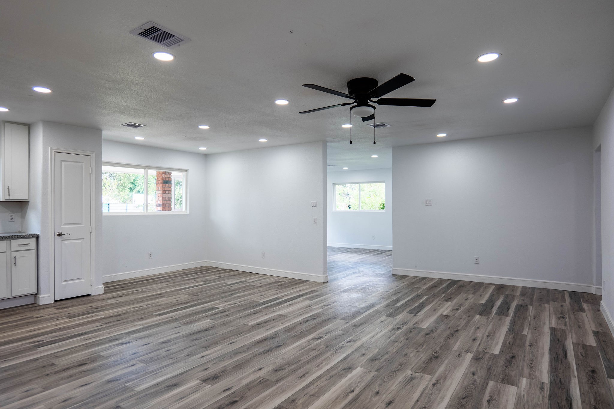 8718 Magna Street Houston, TX 77093 - Photo 8 of 33 an empty room with wooden floor a ceiling fan and windows