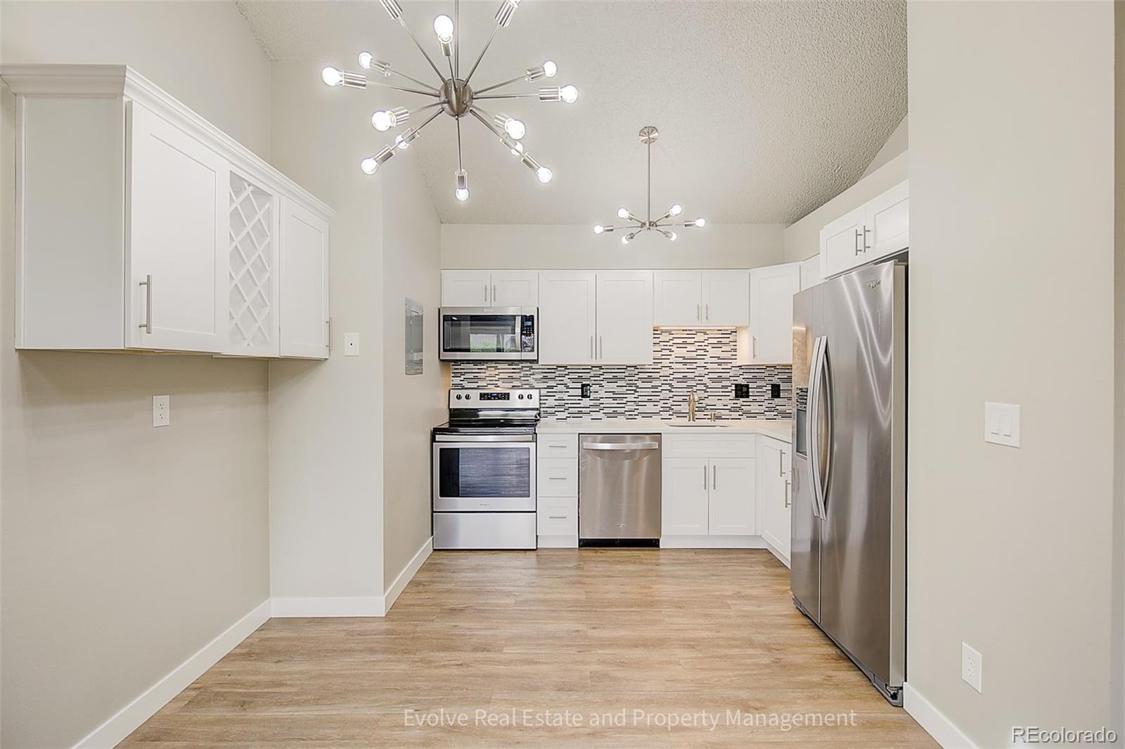 2575 South Syracuse Way, Unit J301 Denver, CO 80231 - Photo 4 of 14 a kitchen with white cabinets and stainless steel appliances