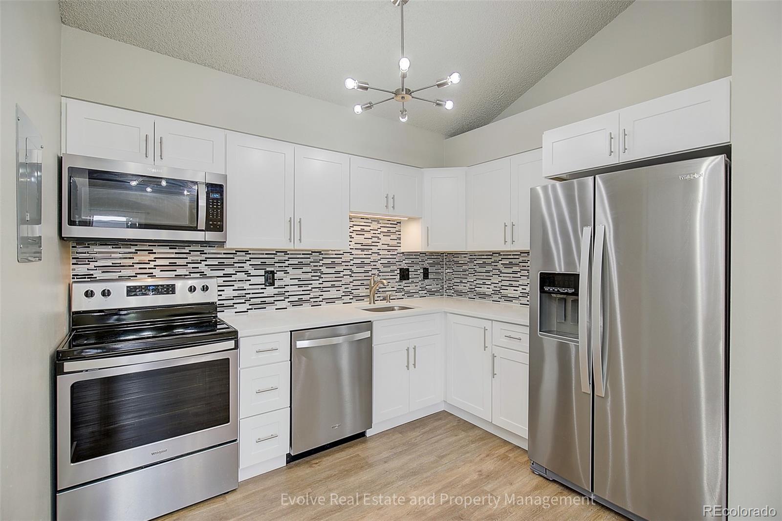 2575 South Syracuse Way, Unit J301 Denver, CO 80231 - Photo 6 of 14 a kitchen with granite countertop a refrigerator stove and microwave