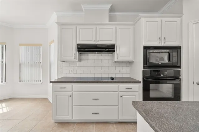 a kitchen with white cabinets and appliances