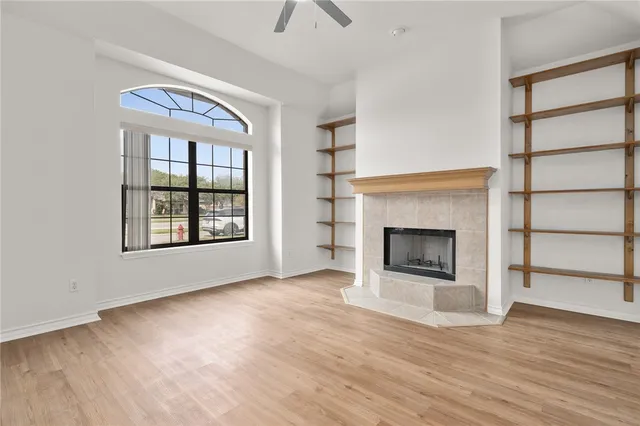 an empty room with wooden floor a fireplace and windows