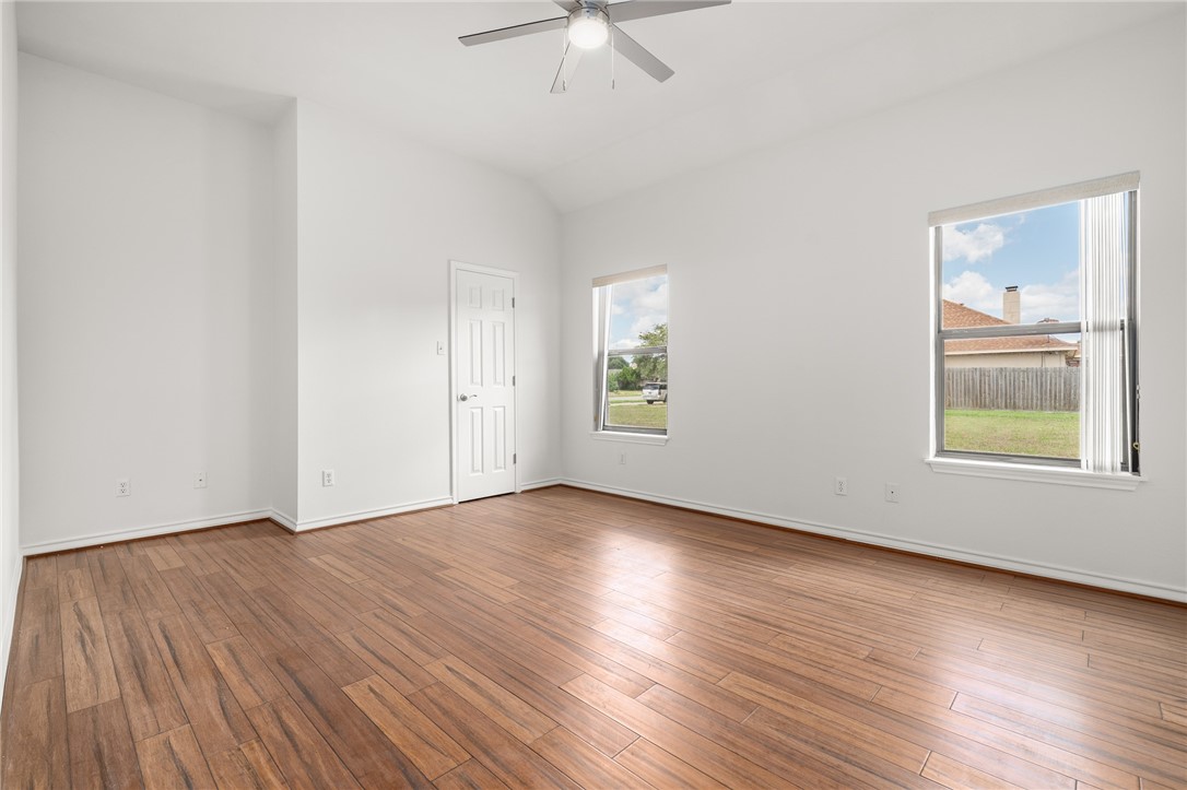 623 Broadway Boulevard Portland, TX 78374 - Photo 23 of 35 an empty room with wooden floor chandelier fan and windows