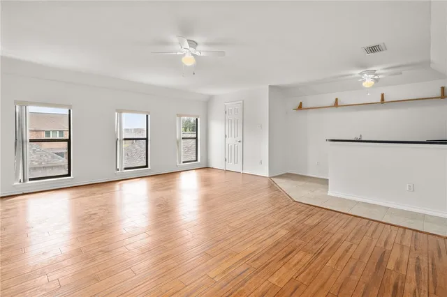a view of an empty room with window and wooden floor