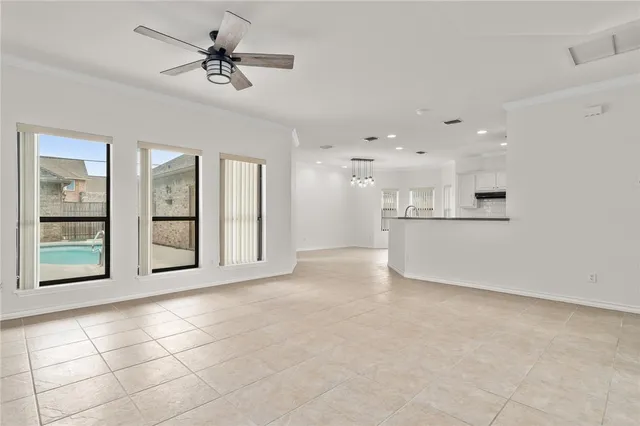 a big room with chandelier fan and windows