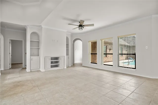 an empty room with windows and ceiling fan