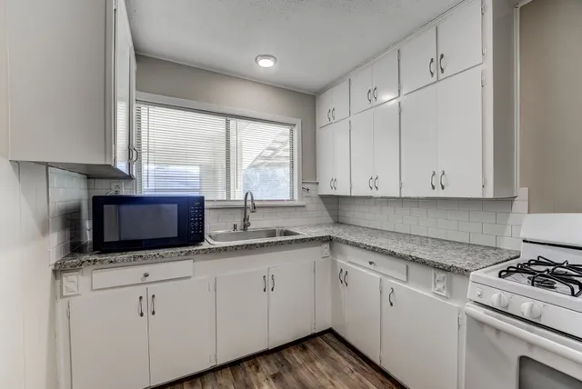 a kitchen with granite countertop white cabinets and white appliances