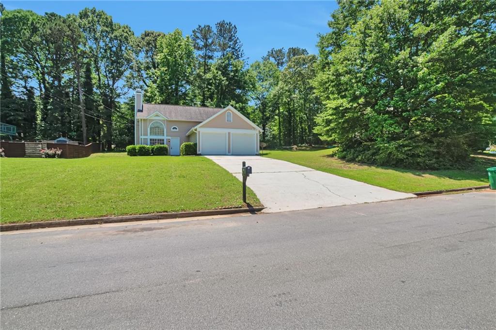 a view of a house with a yard and large trees