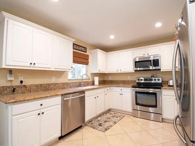 a kitchen with stainless steel appliances granite countertop a stove a sink and a microwave