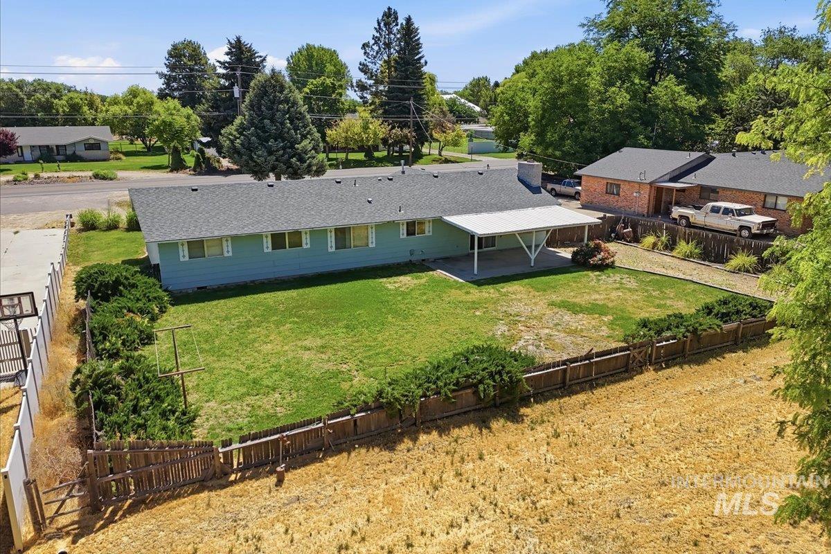 1311 North Middleton Road Nampa, ID 83651 - Photo 14 of 49 Expansive backyard featuring a green lawn, mature perimeter shrubs, and a covered patio area