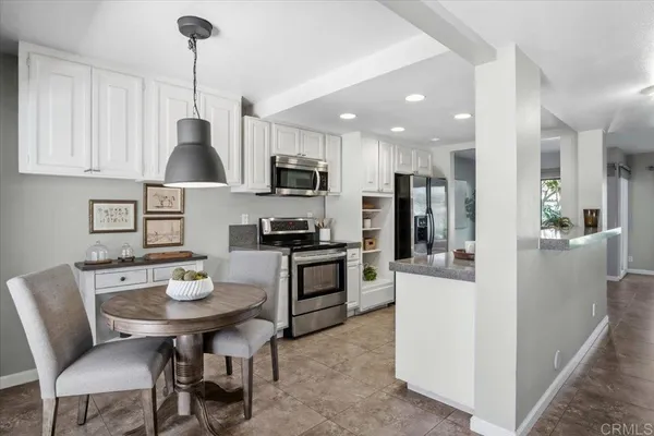 a kitchen with stainless steel appliances kitchen island granite countertop a sink a stove a refrigerator a dining table and chairs