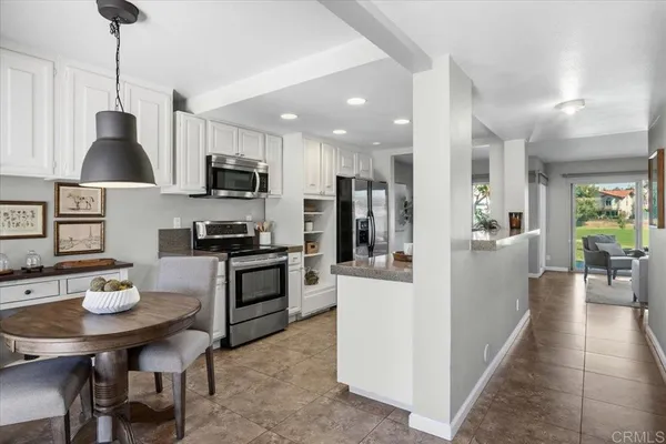 a kitchen with stainless steel appliances kitchen island granite countertop a refrigerator a stove a sink dishwasher a dining table and chairs with wooden floor