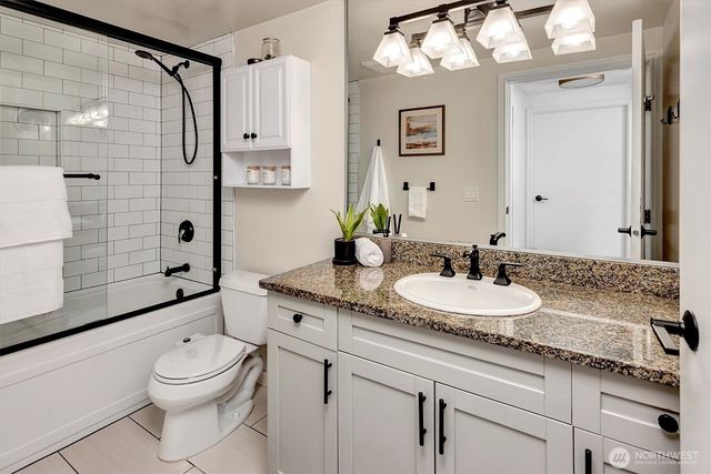 a bathroom with a granite countertop sink a toilet a mirror a bathtub and shower