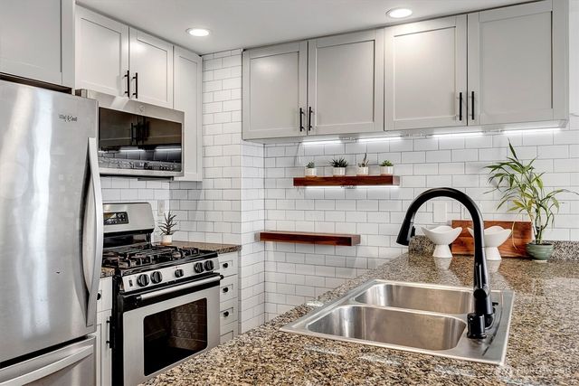 a kitchen with stainless steel appliances granite countertop a sink a stove and cabinets