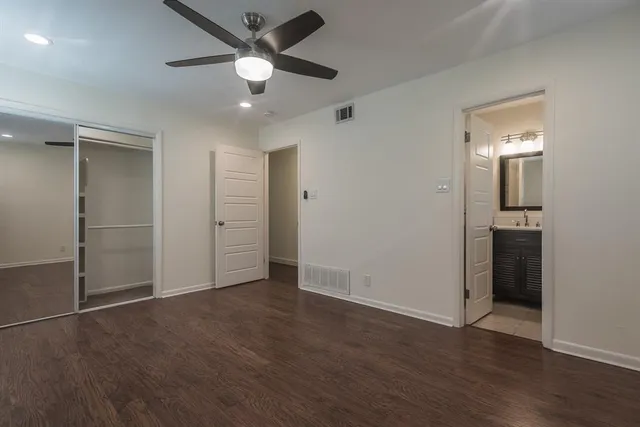 an empty room with wooden floor and ceiling fan