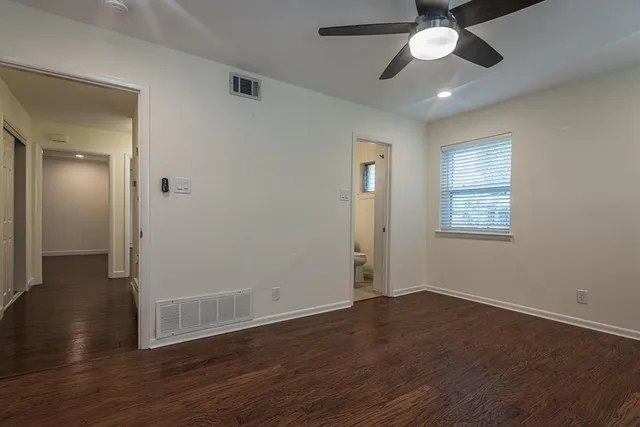 an empty room with wooden floor chandelier fan and windows