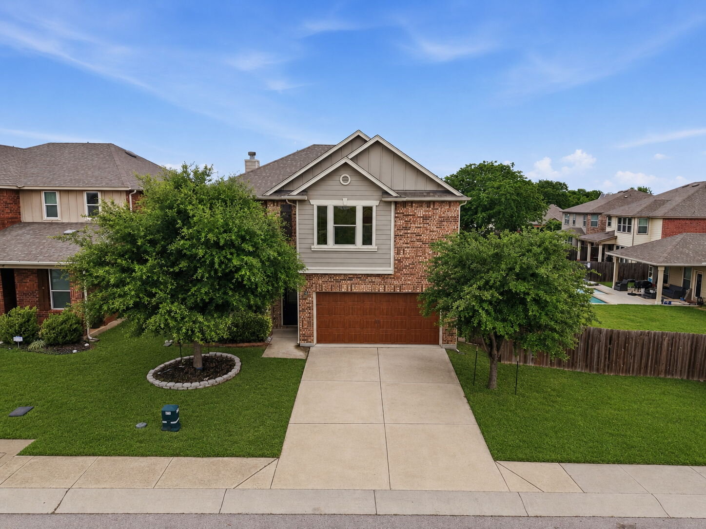 670 Landon Samuel Loop Pflugerville, TX 78660 - Photo 22 of 22 Two-story residence featuring a brick and siding exterior, a wood-finish garage door, and a concrete driveway