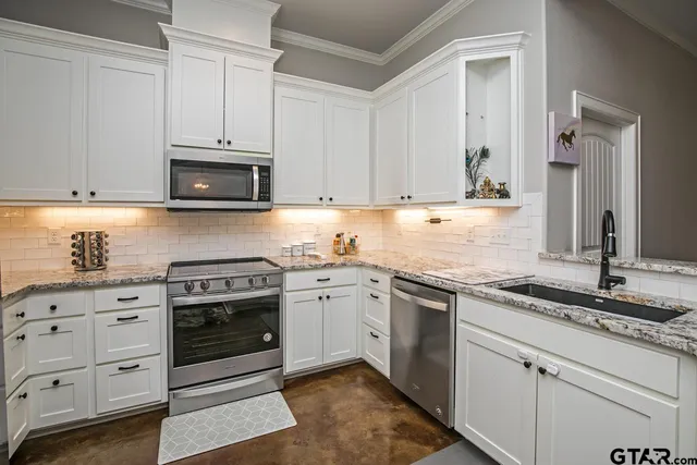 a kitchen with granite countertop white cabinets and stainless steel appliances