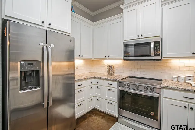 a kitchen with stainless steel appliances white cabinets and a stove top oven