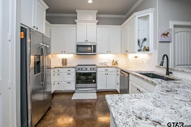 a kitchen with stainless steel appliances kitchen island granite countertop a sink stove and refrigerator