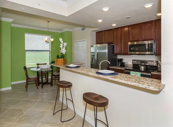 a kitchen with stainless steel appliances granite countertop a refrigerator a stove a sink a dining table and chairs with wooden floor