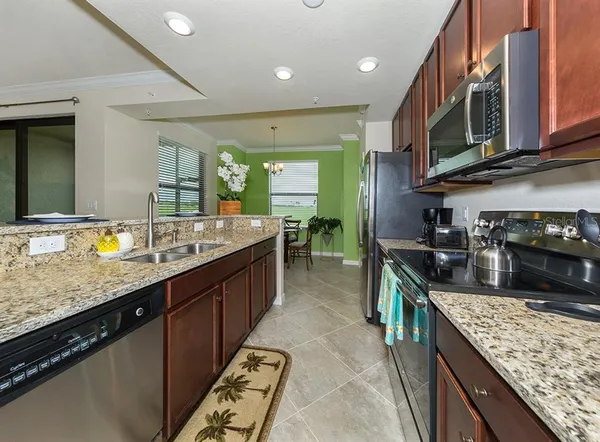 a large kitchen with stainless steel appliances granite countertop a large stove a sink dishwasher a oven and a microwave