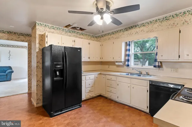 a kitchen with stainless steel appliances granite countertop a refrigerator a sink a stove and white cabinets with wooden floor