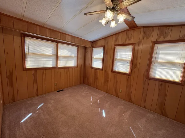 an empty room with windows and fan