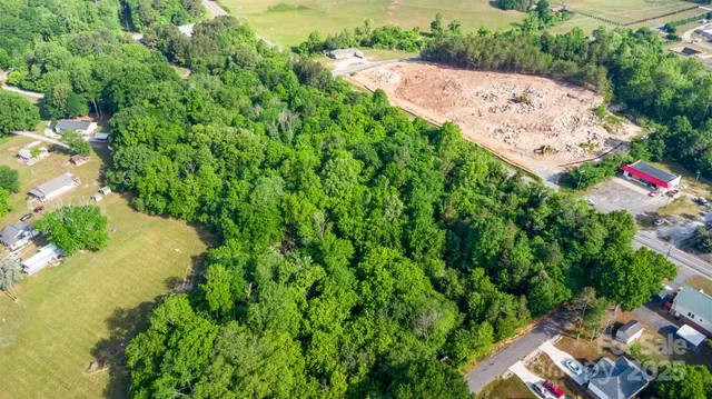 an aerial view of residential house with outdoor space and trees all around