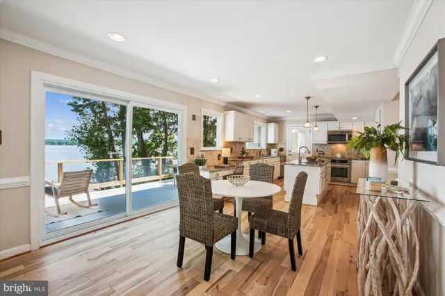 a kitchen with stainless steel appliances granite countertop a refrigerator a stove and a dining table with wooden floor