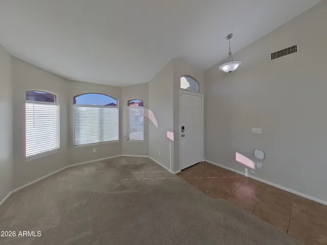 an empty room with chandelier fan and windows