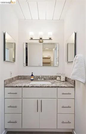 a bathroom with a granite countertop double vanity sink and mirror