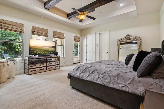 a spacious bedroom with a bed a dresser and a chandelier
