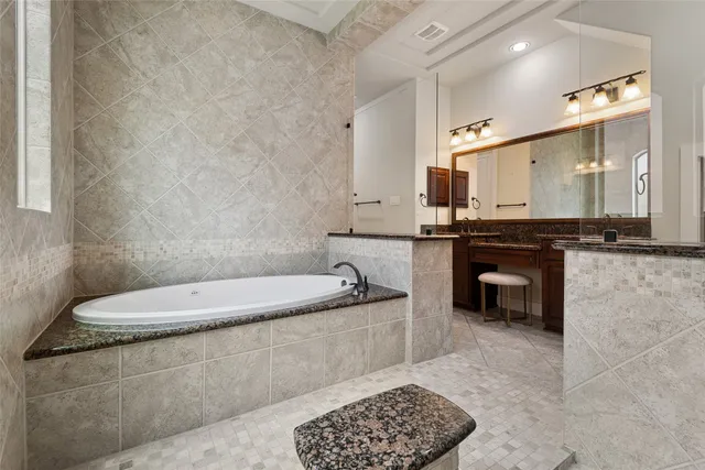 a bathroom with a granite countertop bathtub sink vanity and mirror