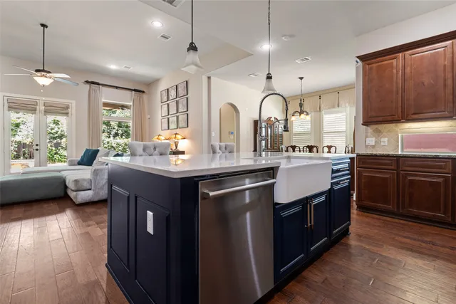 a kitchen with stainless steel appliances granite countertop a sink a stove and a wooden floors