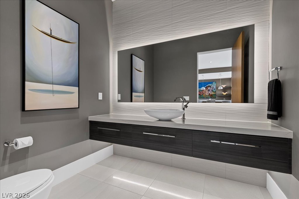 657 Ridgestone Rim Court Henderson, NV 89012 - Photo 79 of 97 Floating cabinetry, stone counters, and an illuminated mirror define this contemporary powder room.